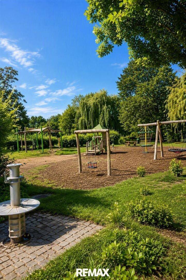 Großer Kinderspielplatz mit Schaukeln und Holzspielgeräten in grüner Umgebung.