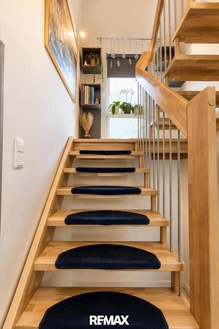 Helle Holztreppe mit dunklen Teppichstufen und modernem Geländer.