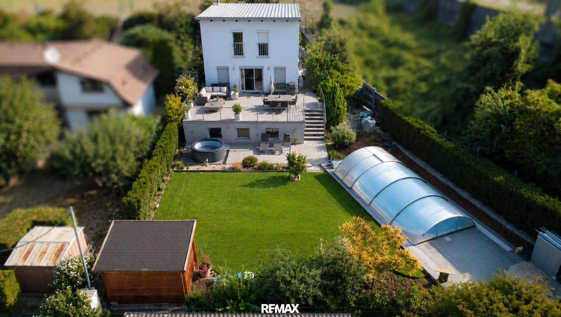 Luftaufnahme eines Hauses mit großem Garten, Pool, Terrasse und Whirlpool.