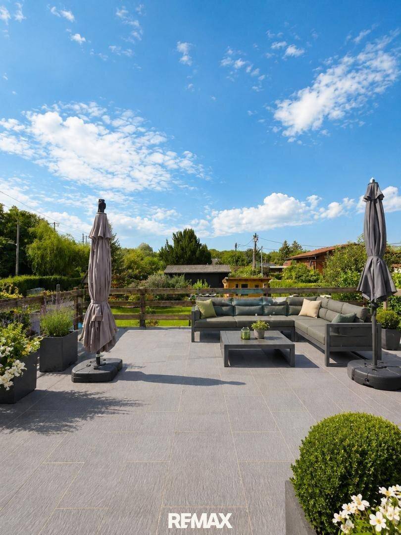 Geräumige Terrasse mit modernen Lounge-Möbeln und Sonnenschirmen, ideal zum Entspannen.