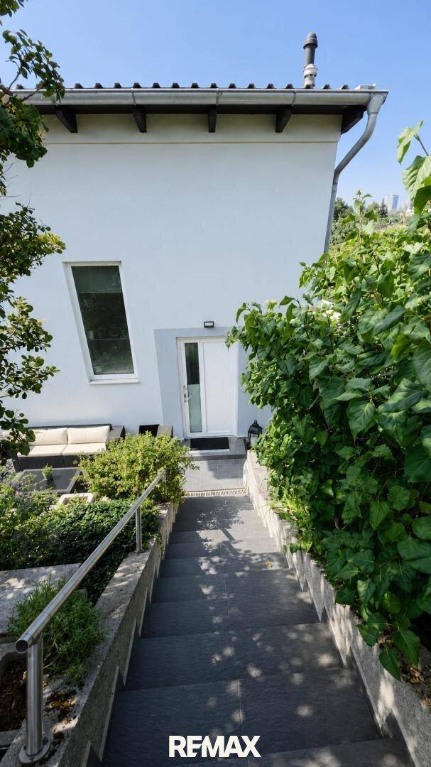 Eingangsbereich des Hauses mit Steintreppe und üppiger Bepflanzung.