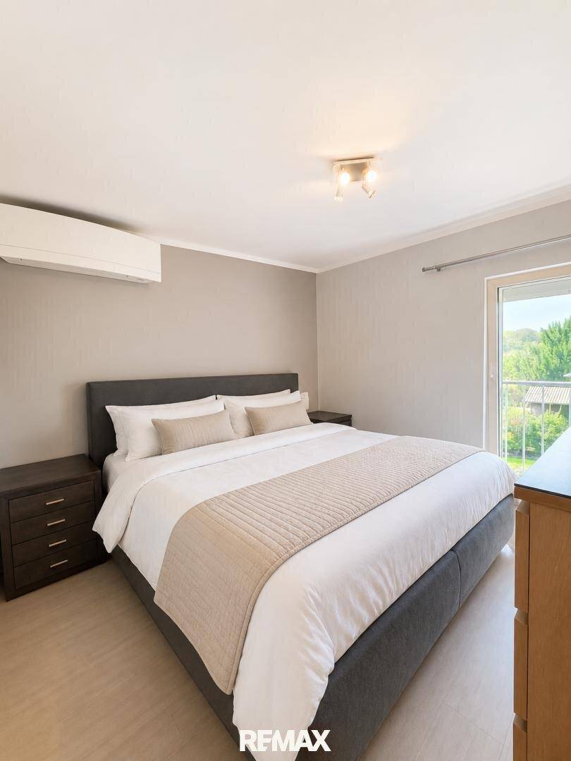 Helles Schlafzimmer mit großem Doppelbett, Klimaanlage und Zugang zum Balkon.