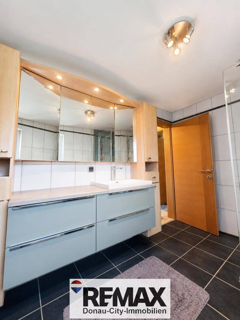 Badezimmer mit modernem Waschtischunterschrank, Einzelwaschbecken und Spiegelschrank.