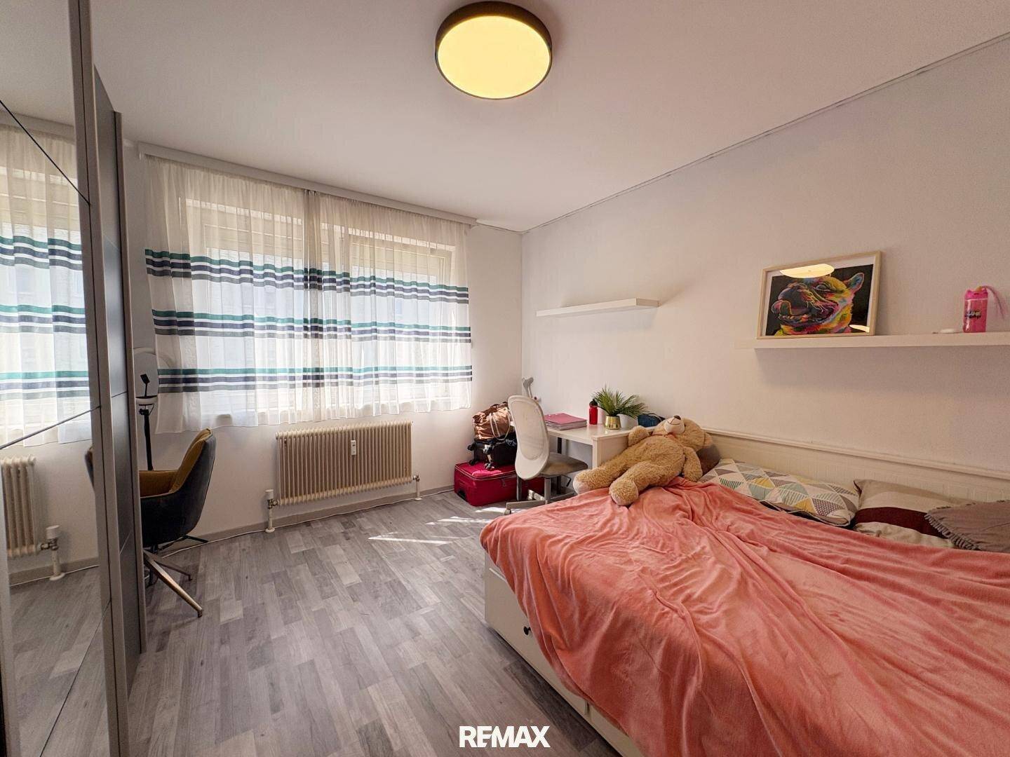 Helles Schlafzimmer mit Einzelbett, Schreibtisch und großem Fenster, ideal für Jugendliche.