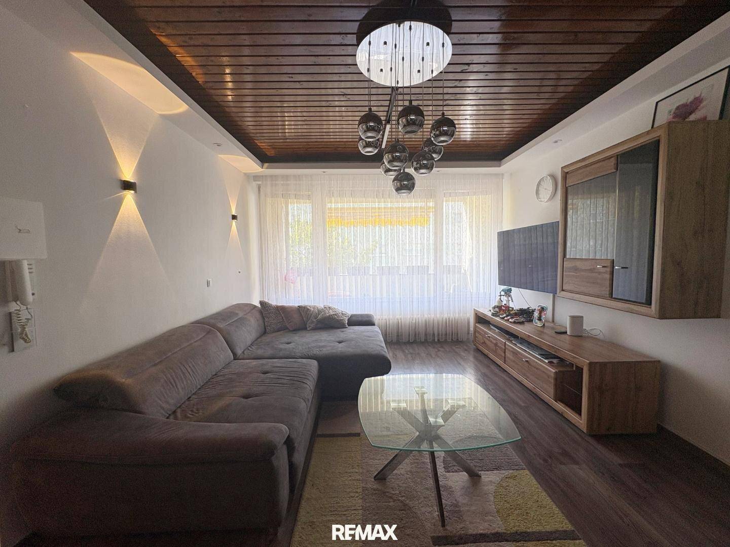 Gemütliches Wohnzimmer mit Holzbalkendecke, großem Sofa und modernem Unterhaltungsmöbel.