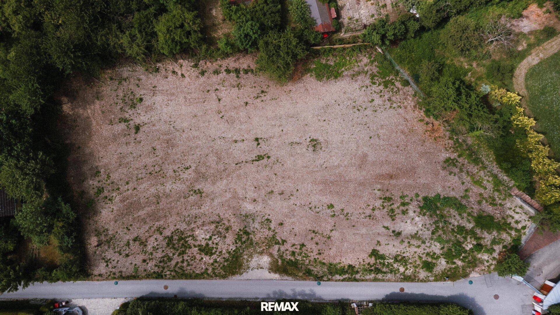 Luftaufnahme von oben eines unbebauten Grundstücks mit angrenzender Straße.