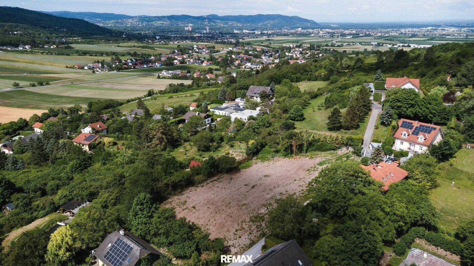 Panoramablick aus der Luft auf ein Grundstück umgeben von Natur und Wohnbebauung.