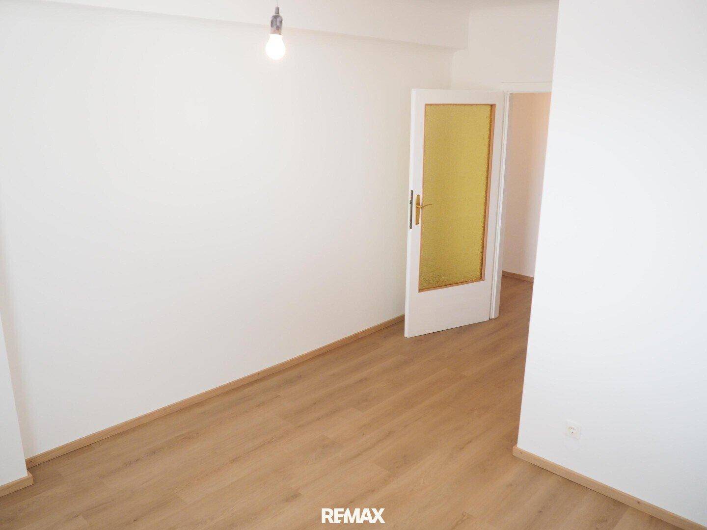 Helles Zimmer mit Laminatboden und Tür mit Glaseinsatz, bietet vielseitige Nutzungsmöglichkeiten.