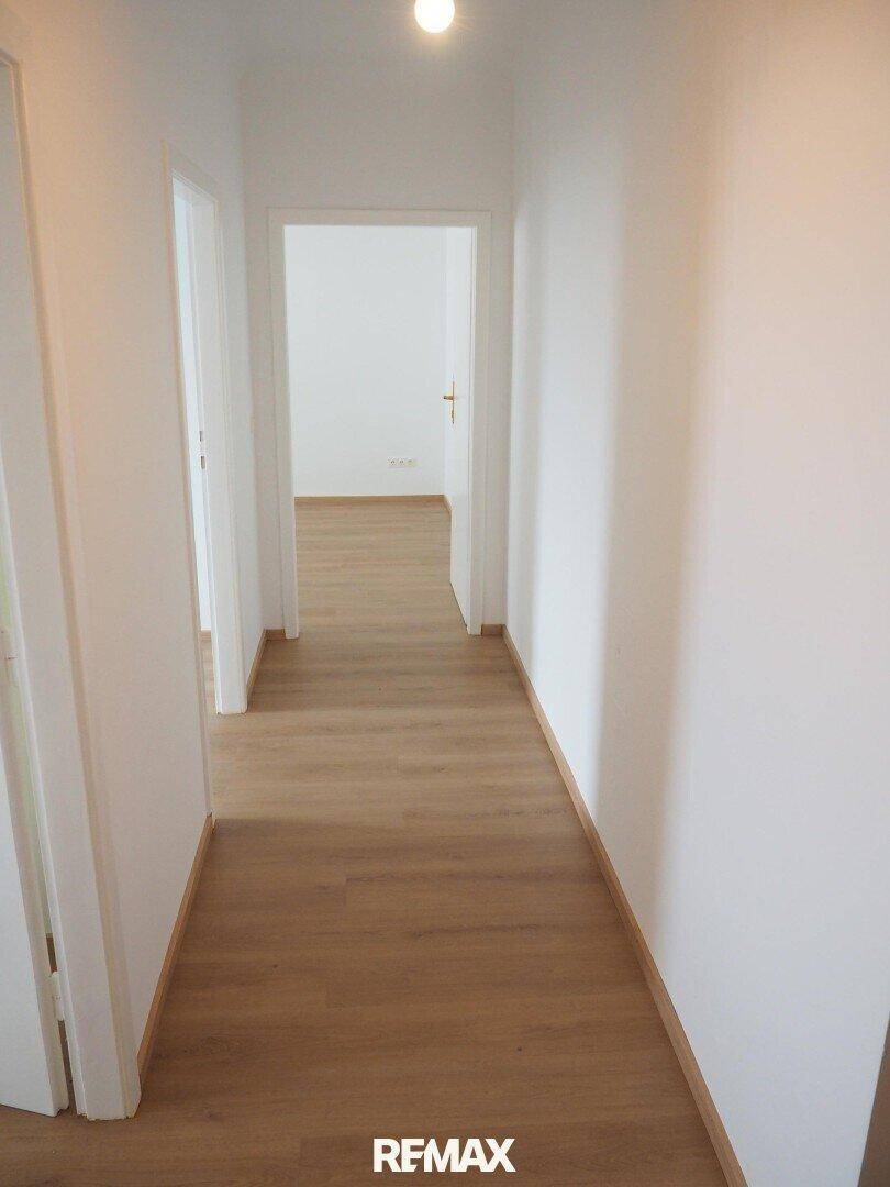 Langer, heller Flur mit Laminatboden, der zu weiteren Zimmern führt.