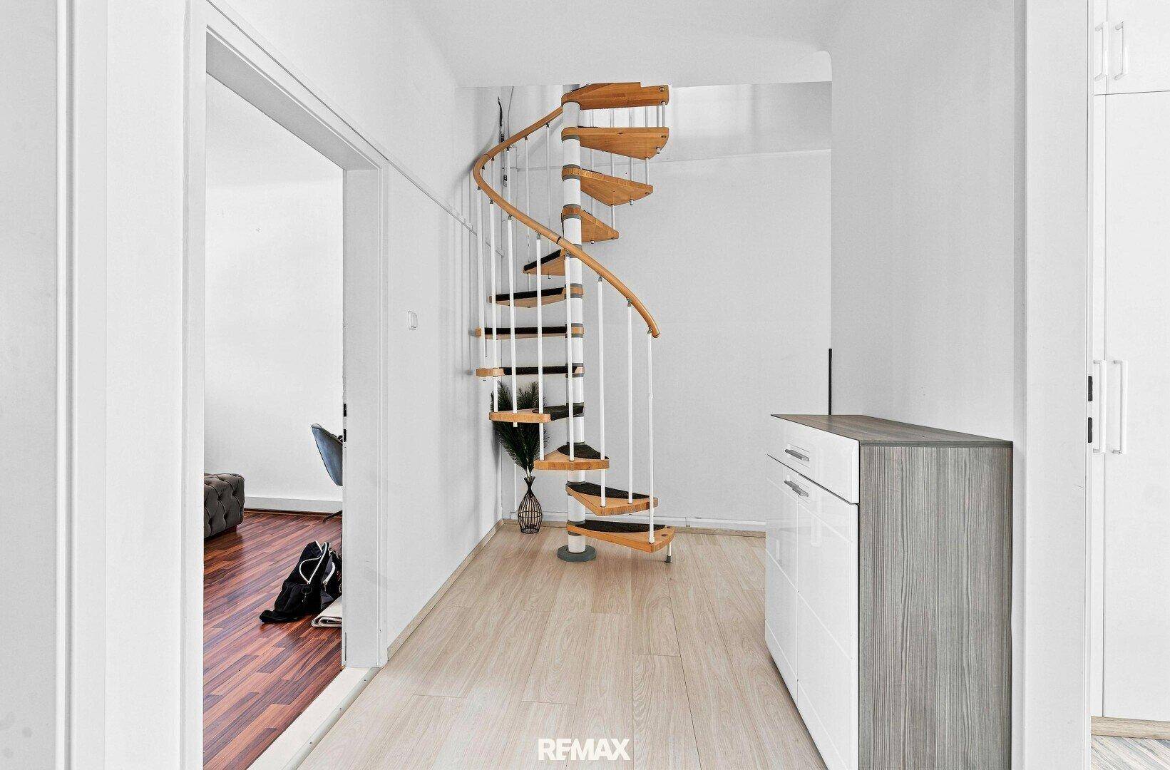 Heller Flur mit einer eleganten Holz-Wendeltreppe und Laminatboden, der verschiedene Ebenen verbindet.