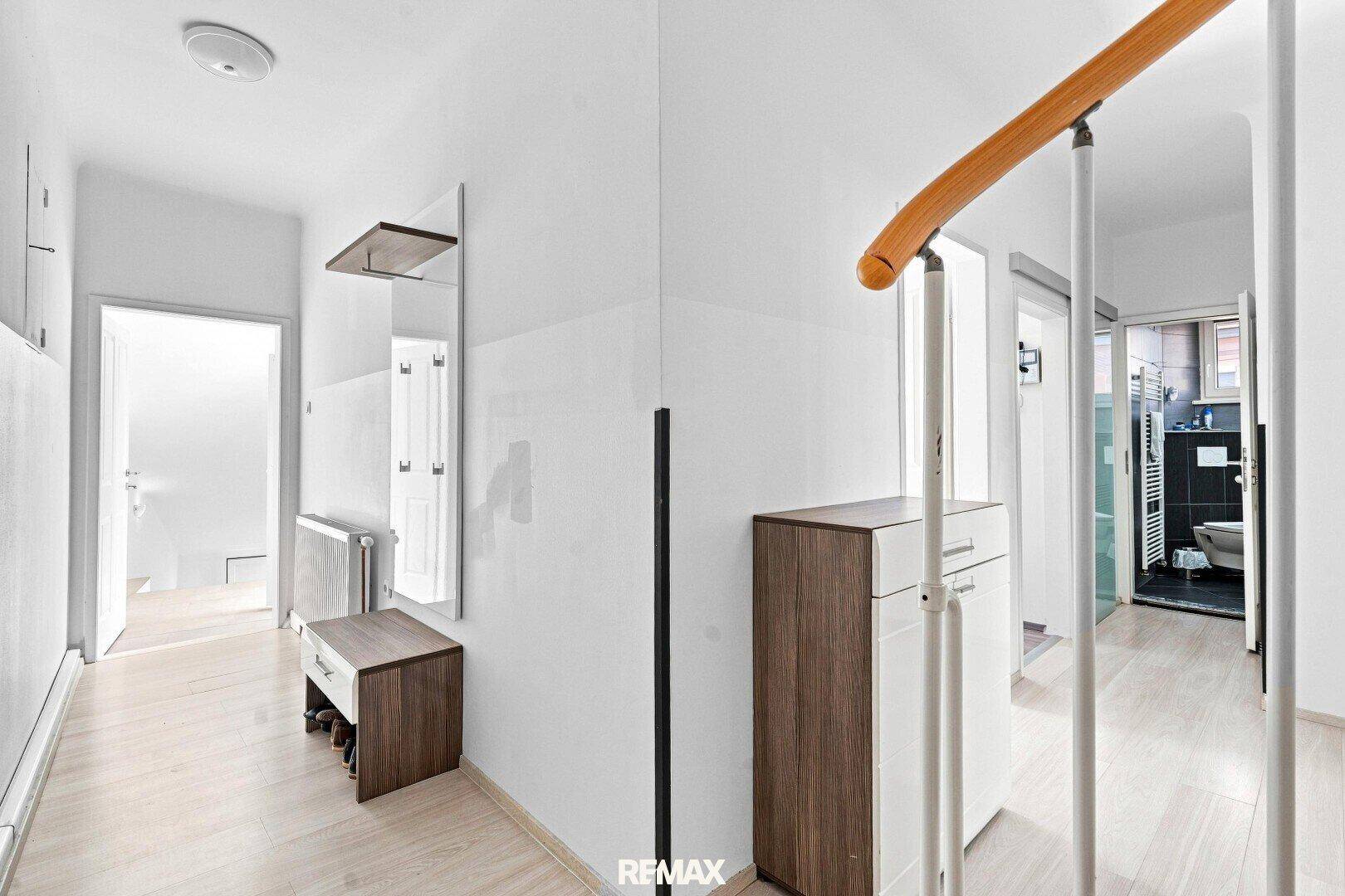 Heller Flur mit Garderobe, Spiegel und Zugang zu weiteren Räumen, inklusive Badezimmer.