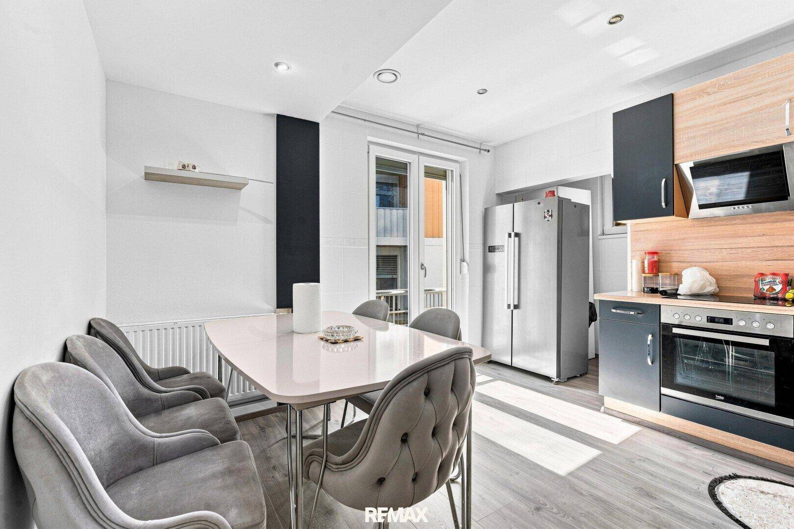 Funktionale Wohnküche mit Essbereich, modernen Geräten und Zugang zu einem Balkon.