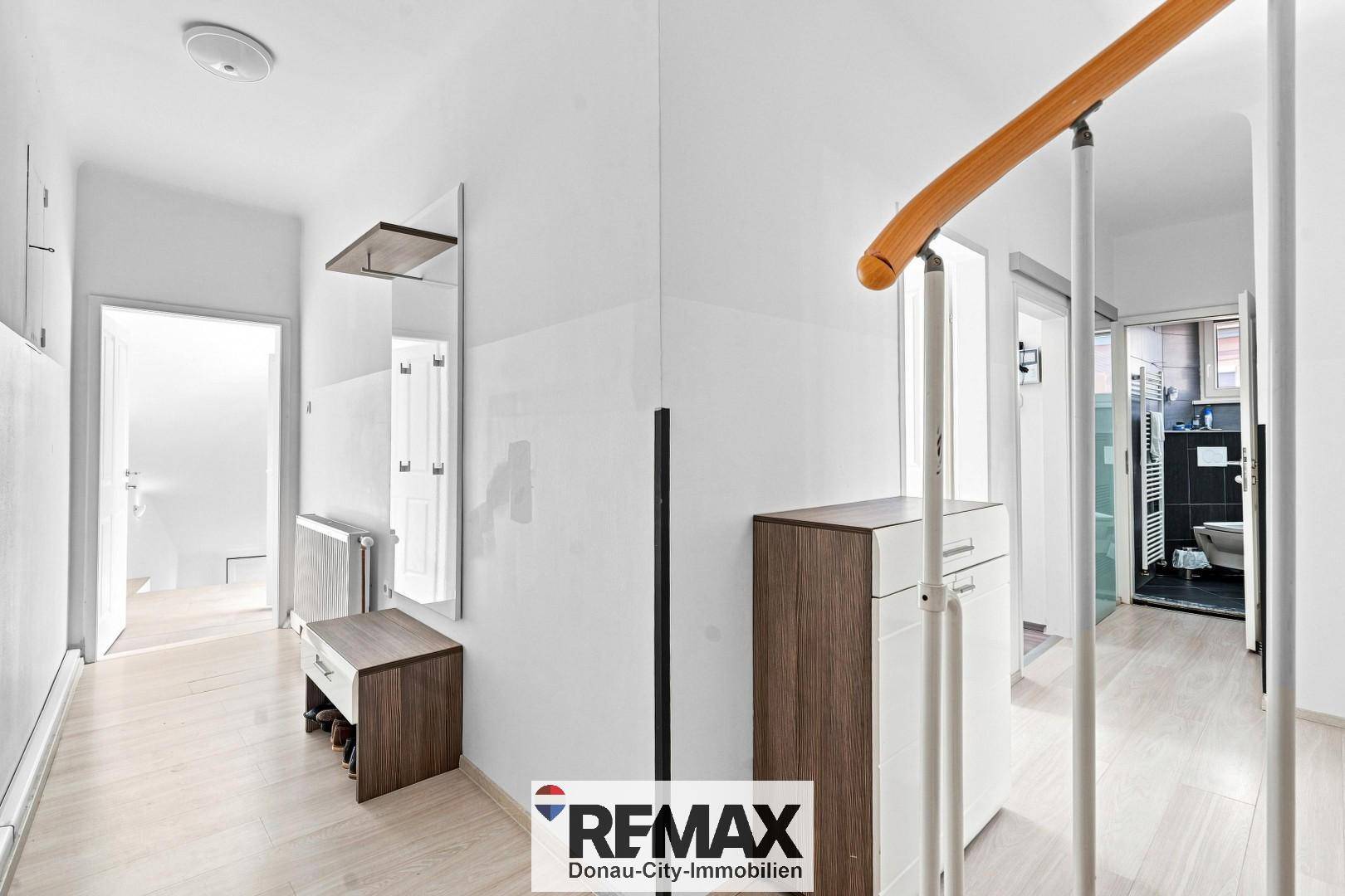 Heller Eingangsbereich mit Garderobe, Spiegel und Zugang zu weiteren Räumen.