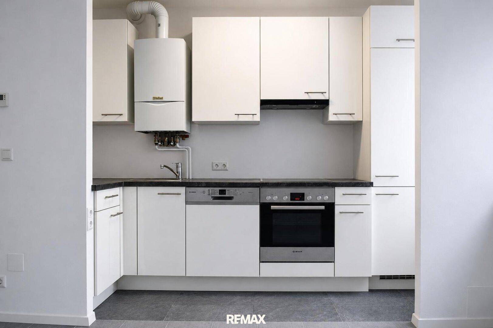Funktionale Küche mit weißen Schränken, integriertem Geschirrspüler und Backofen.
