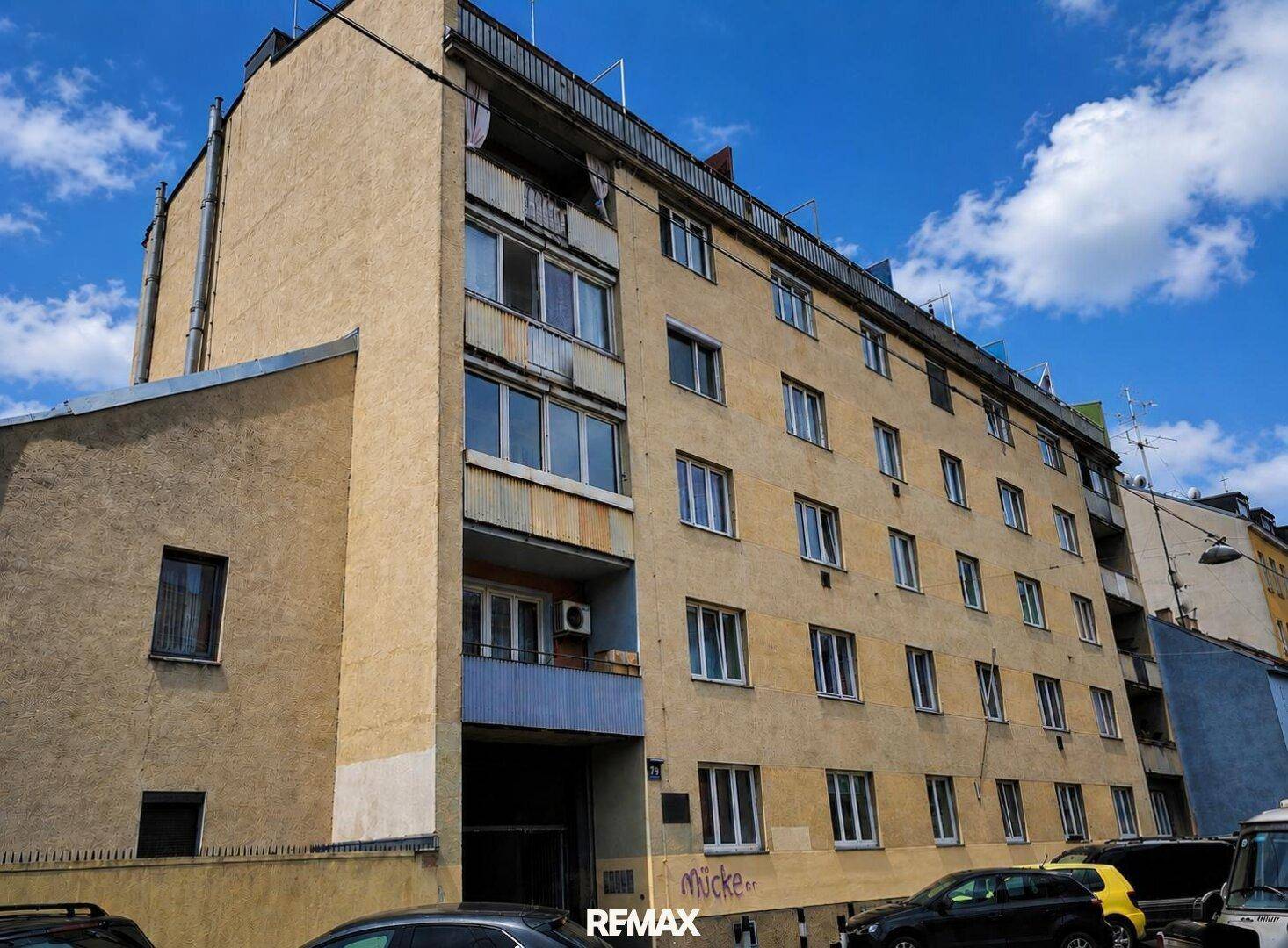 Ansicht eines älteren Mehrfamilienhauses mit mehreren Etagen und Balkonen.