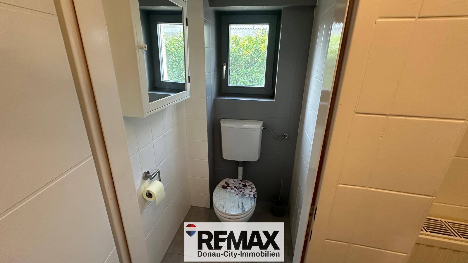 Kleines Gäste-WC mit Toilette, Spiegelschrank und einem Fenster für Tageslicht.