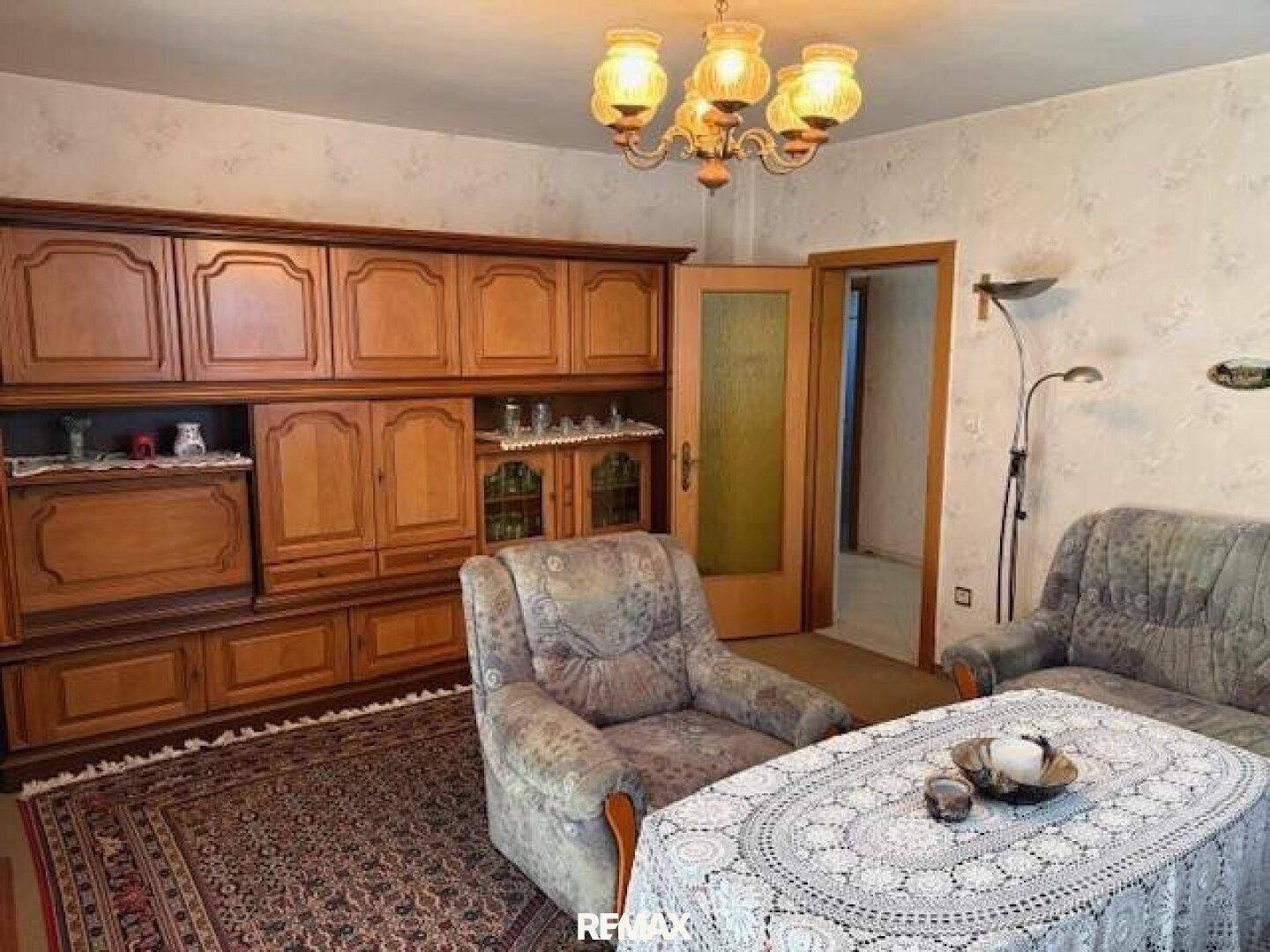 Gemütliches Wohnzimmer mit traditionellen Holzmöbeln, Teppich und bequemen Sesseln.