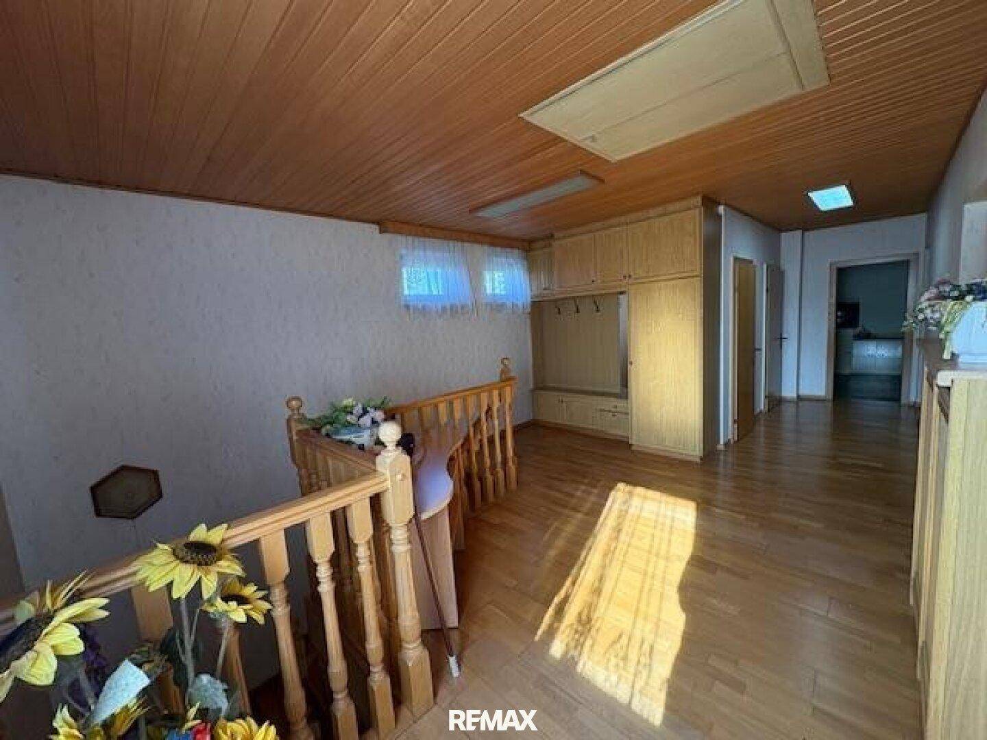 Heller Flur im Obergeschoss mit Holzparkett, Holzdecke und Einbauschränken.