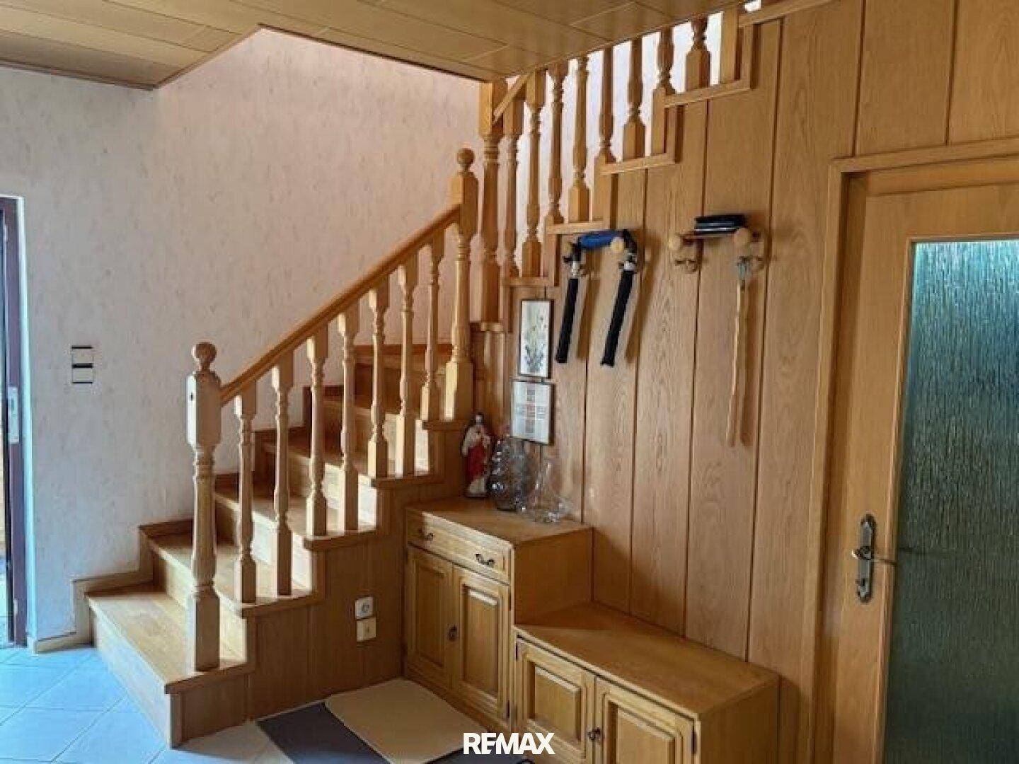 Holztreppe im Eingangsbereich mit Holzvertäfelung und traditionellen Möbeln.