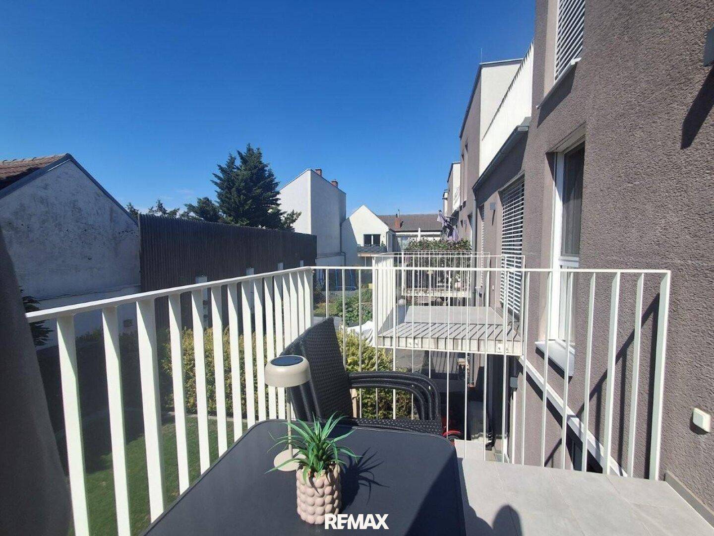 Sonniger Balkon mit Sitzgelegenheiten und Blick auf die Nachbarschaft, perfekt zum Entspannen.