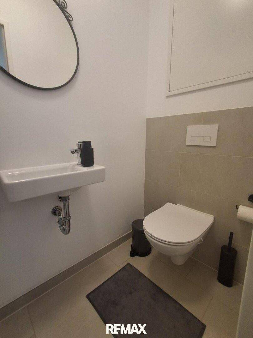 Modernes Gäste-WC mit wandhängender Toilette und kleinem Waschbecken, sauber und funktional.