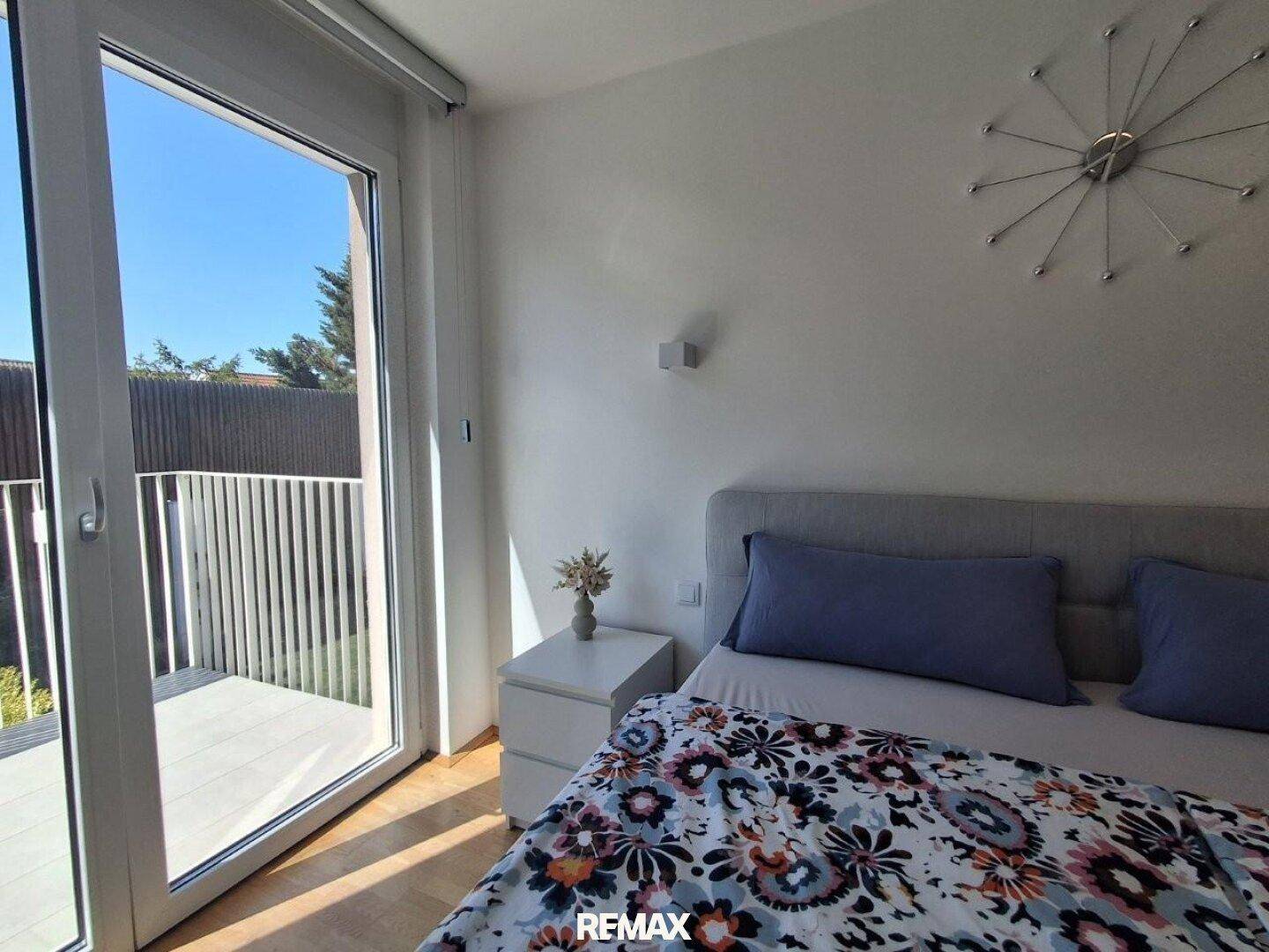 Schlafzimmer mit Bett und großzügigem Zugang zu einem privaten Balkon, hell und einladend.