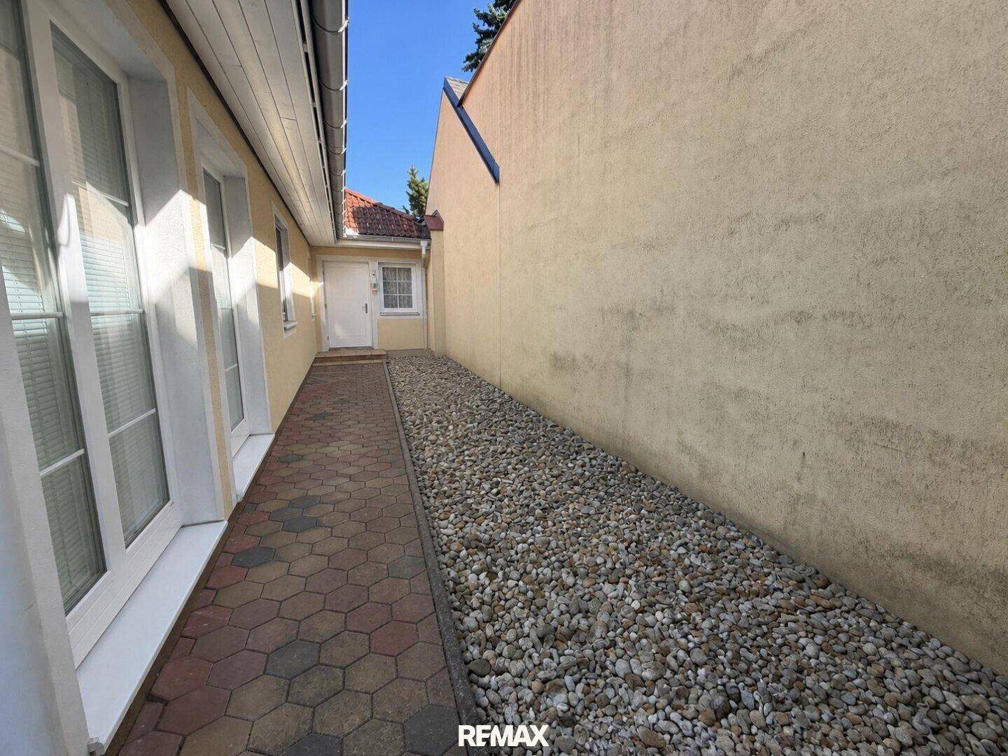 Kiesweg entlang der Hauswand, bietet Zugang zum hinteren Teil des Grundstücks.