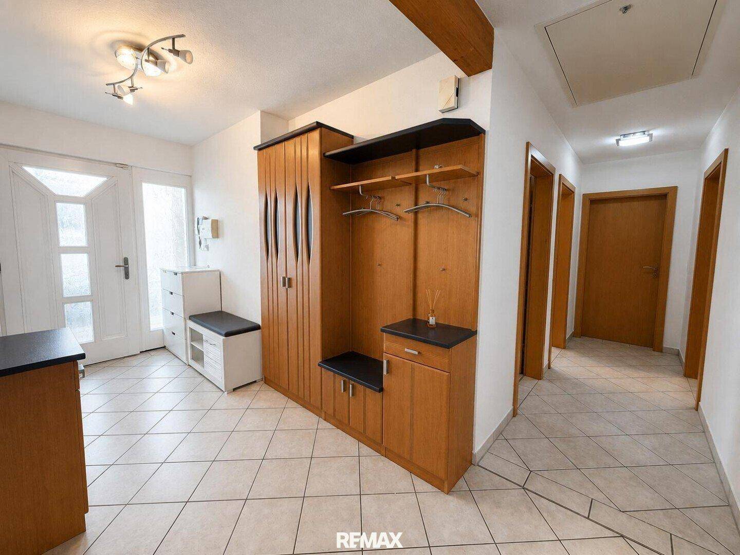 Heller Eingangsbereich mit Fliesenboden und Garderobe, führt zu weiteren Räumen.