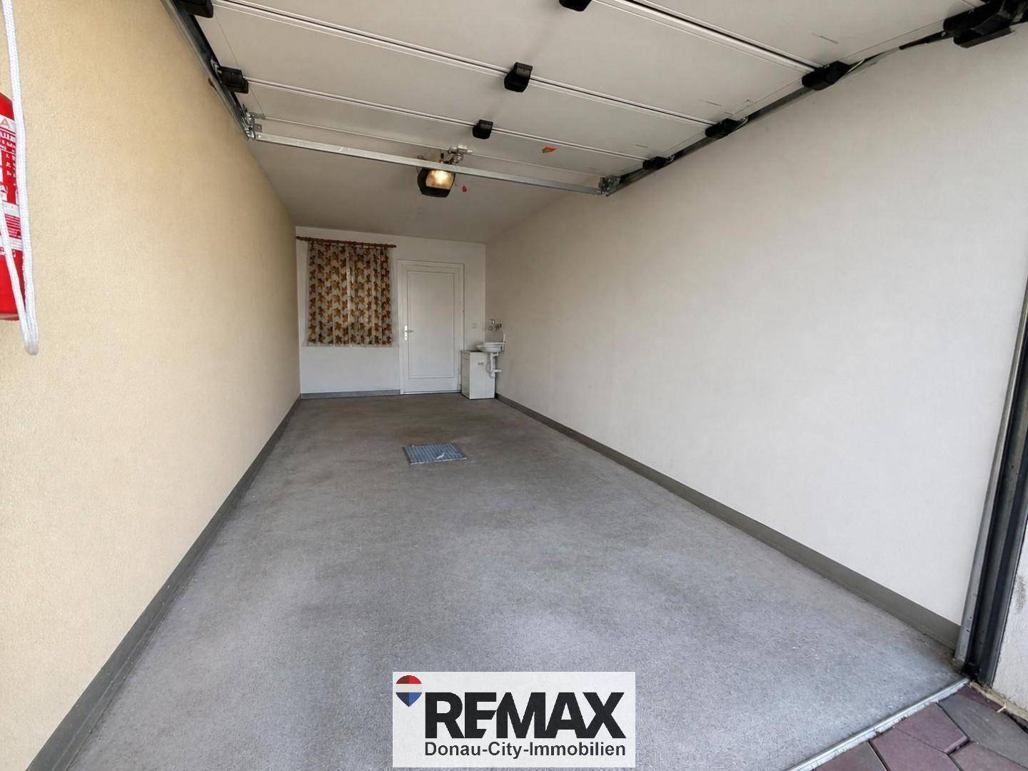 Geräumige Garage mit Betonboden und weiß gestrichenen Wänden, bereit zur Nutzung.