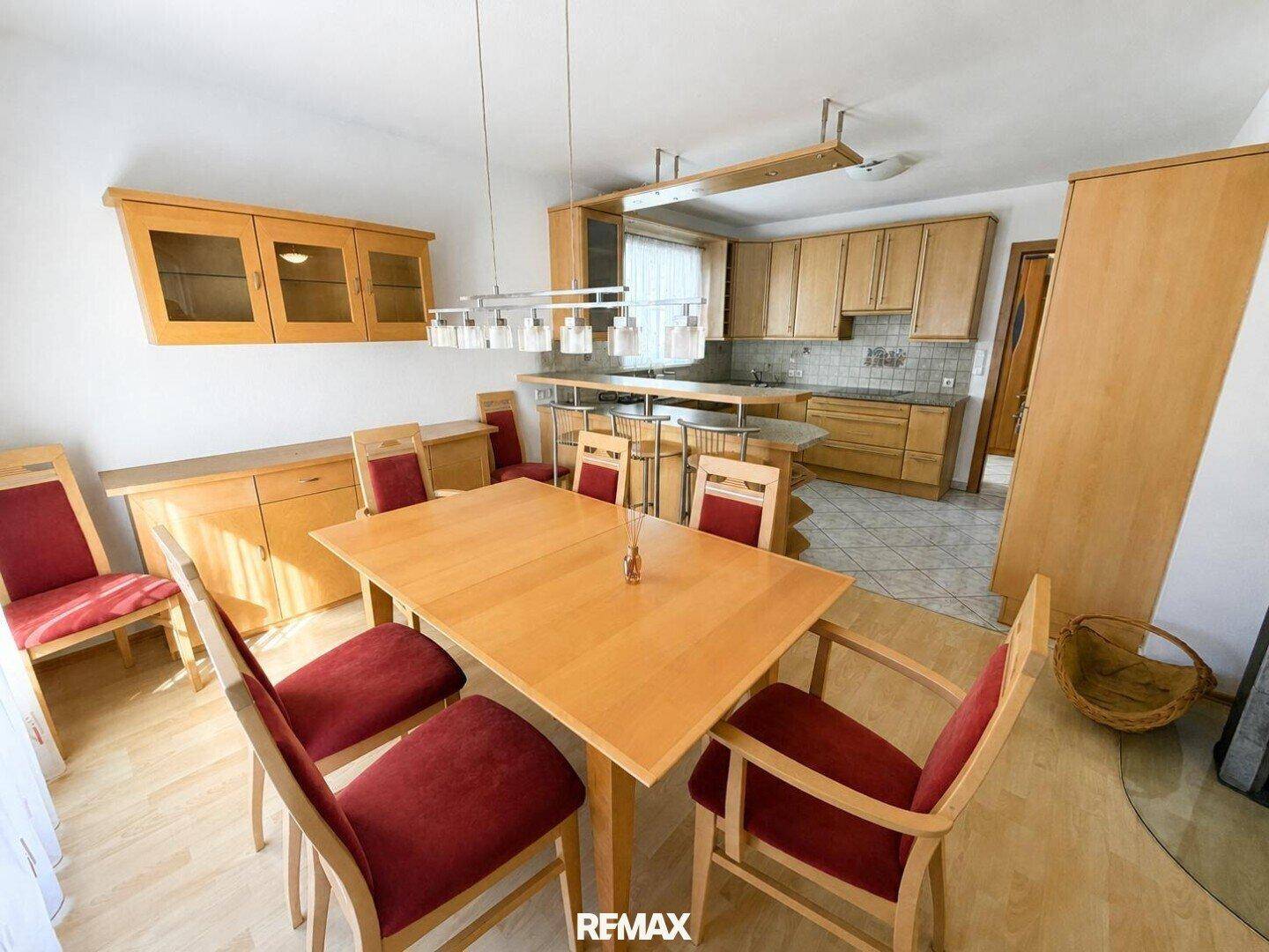 Essbereich mit Holztisch und Stühlen, offen zur Küche mit Holzschränken.