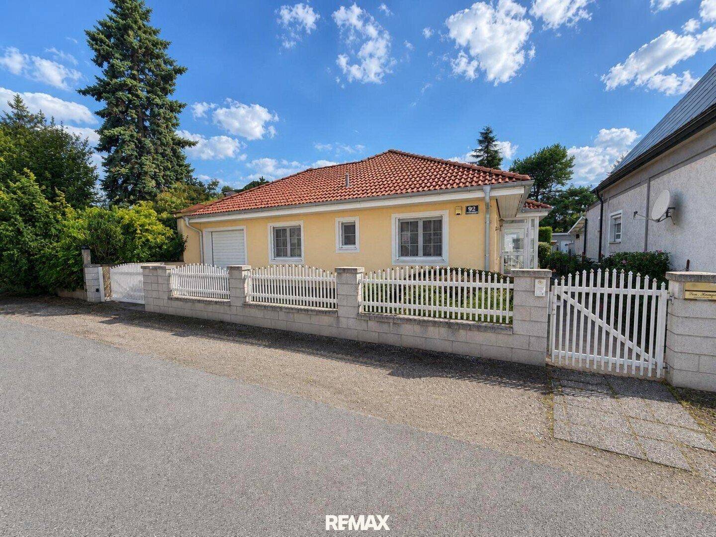 Ansicht des Hauses von der Straße mit weißem Zaun und gepflegtem Vorgarten.