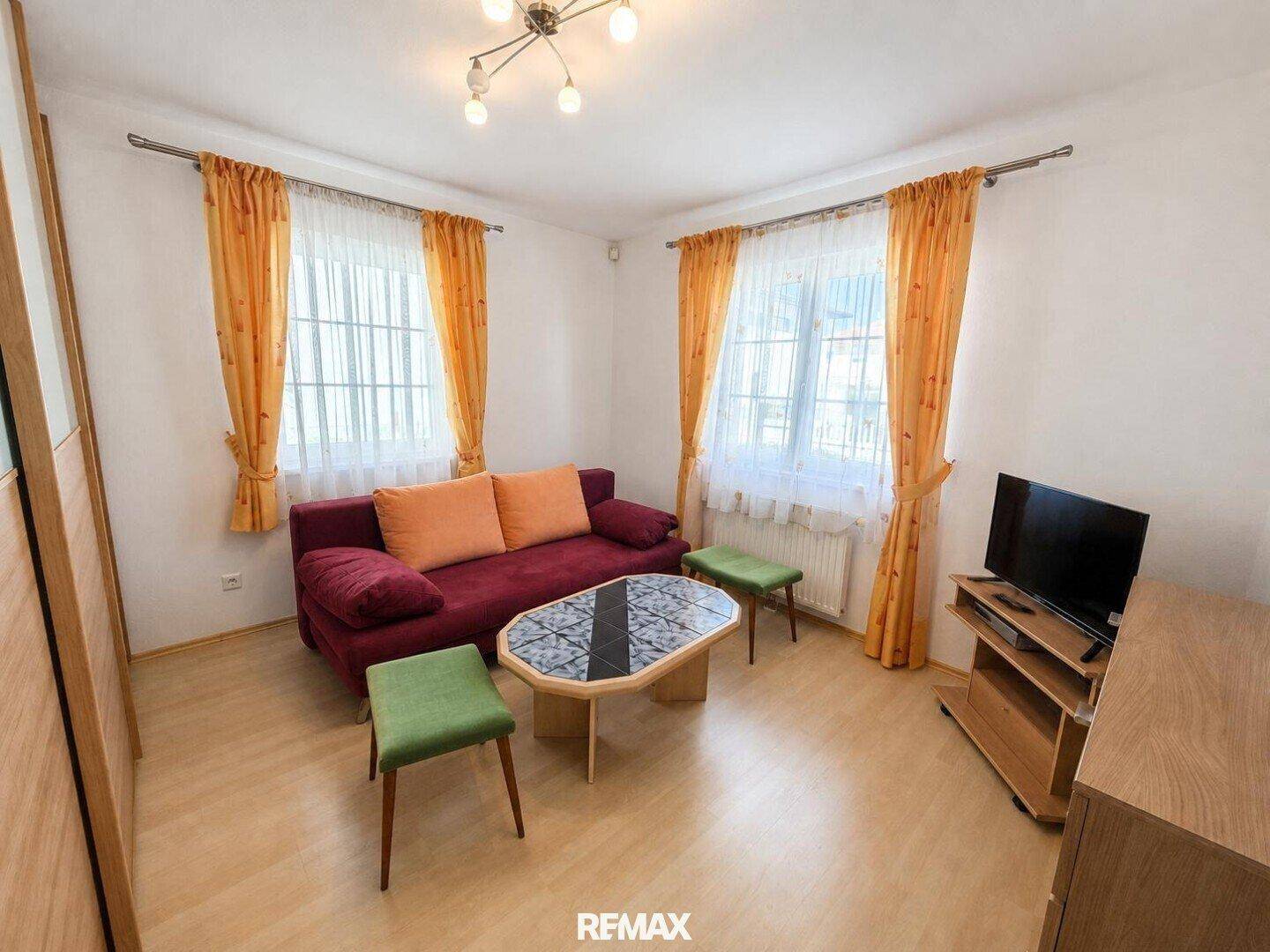 Helles Schlafzimmer mit Laminatboden und farbenfrohen Vorhängen, bietet eine gemütliche Atmosphäre.