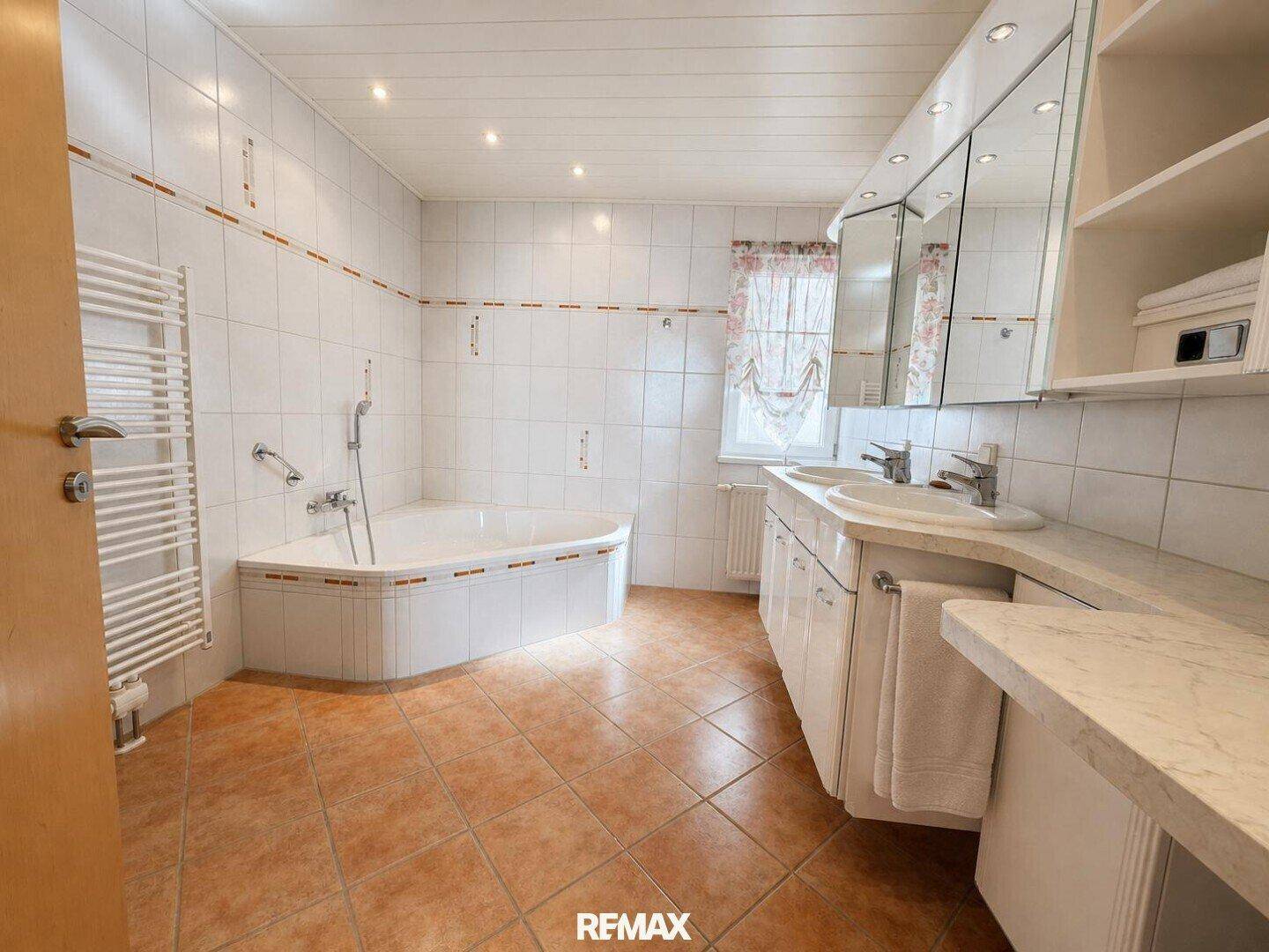Geräumiges Badezimmer mit Eckbadewanne, Doppelwaschbecken und beheiztem Handtuchhalter.