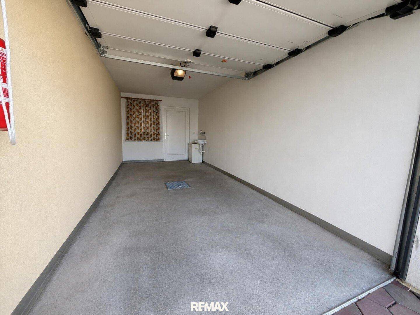 Geräumige Garage mit Betonboden und Fenster, bietet Platz für ein Fahrzeug.