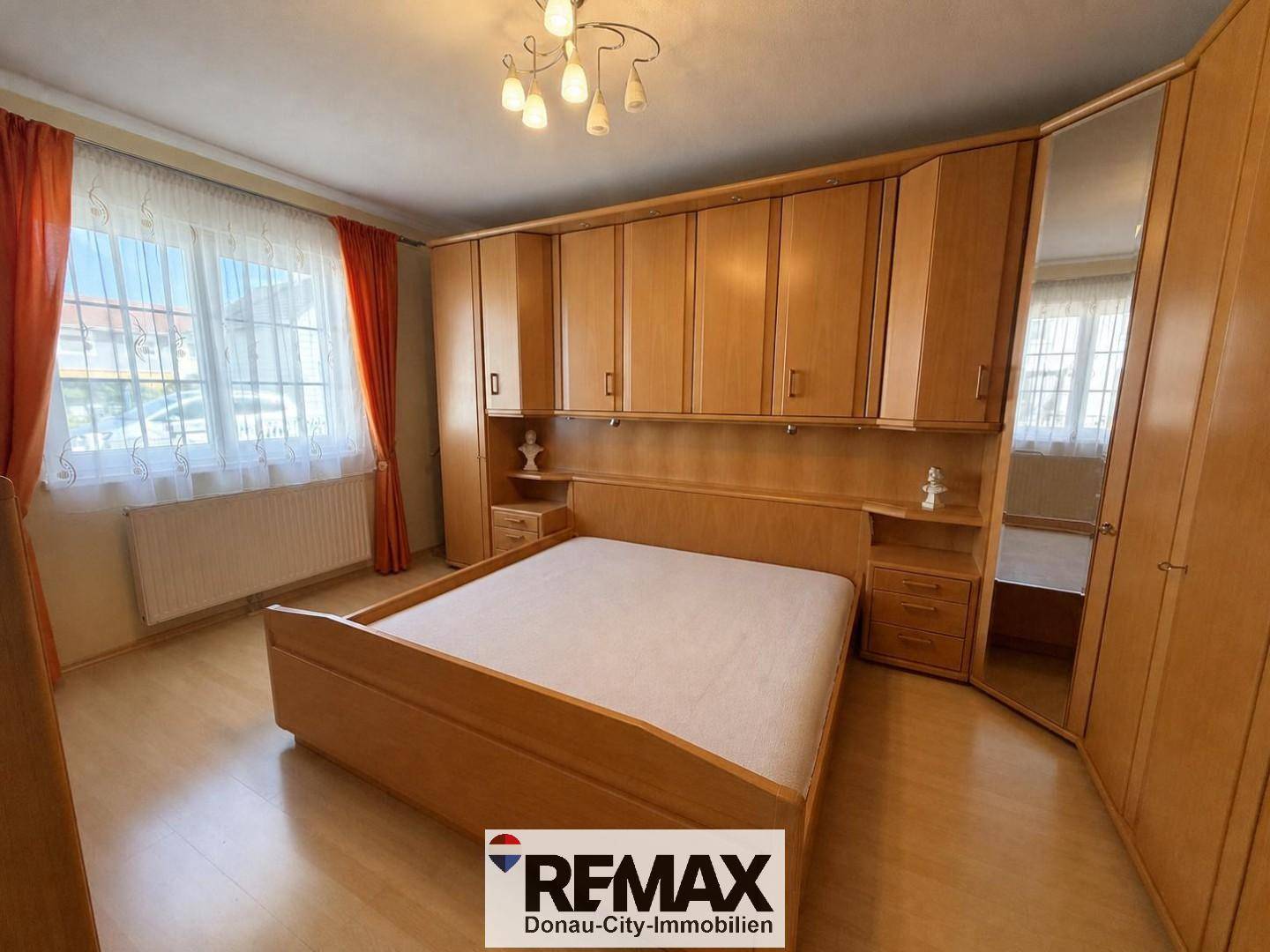 Gemütliches Schlafzimmer mit Holzbett, Einbauschränken und Laminatboden.