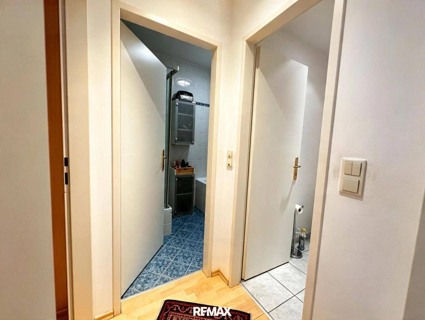 Flur mit Zugang zu Badezimmer und separatem WC, beide mit Fliesenböden.