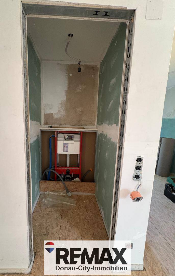 Badezimmer im Rohbau mit vorbereiteter Installation für Wand-WC und Waschbecken.