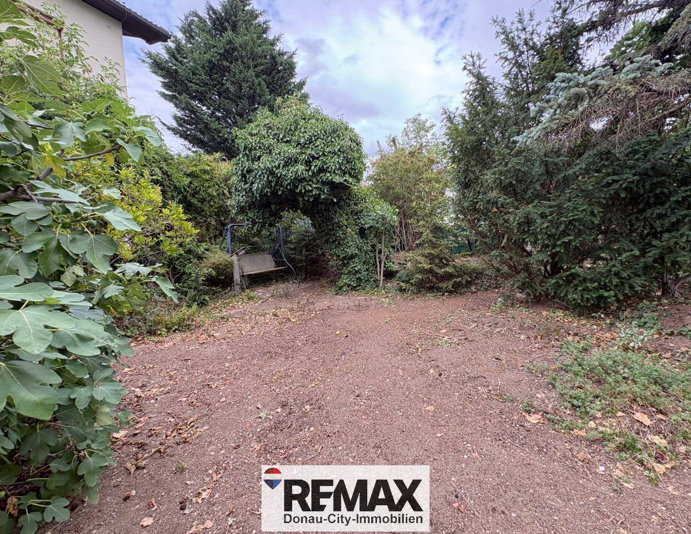 Großer Gartenbereich mit Bäumen, Sträuchern und einer Schaukel, ideal für Familien.