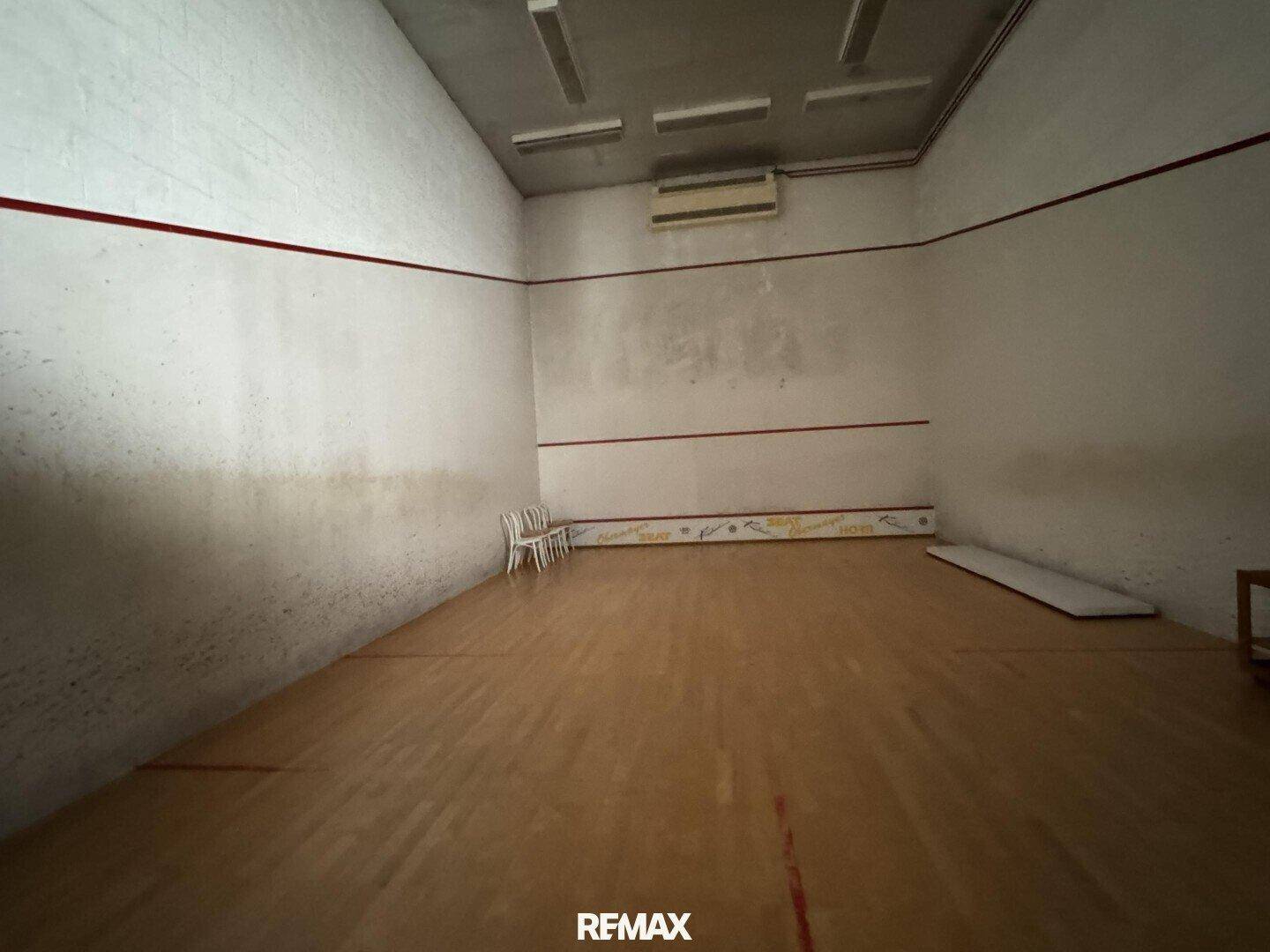 Squash-Court mit Holzboden und markierten Wänden, bereit für sportliche Aktivitäten.