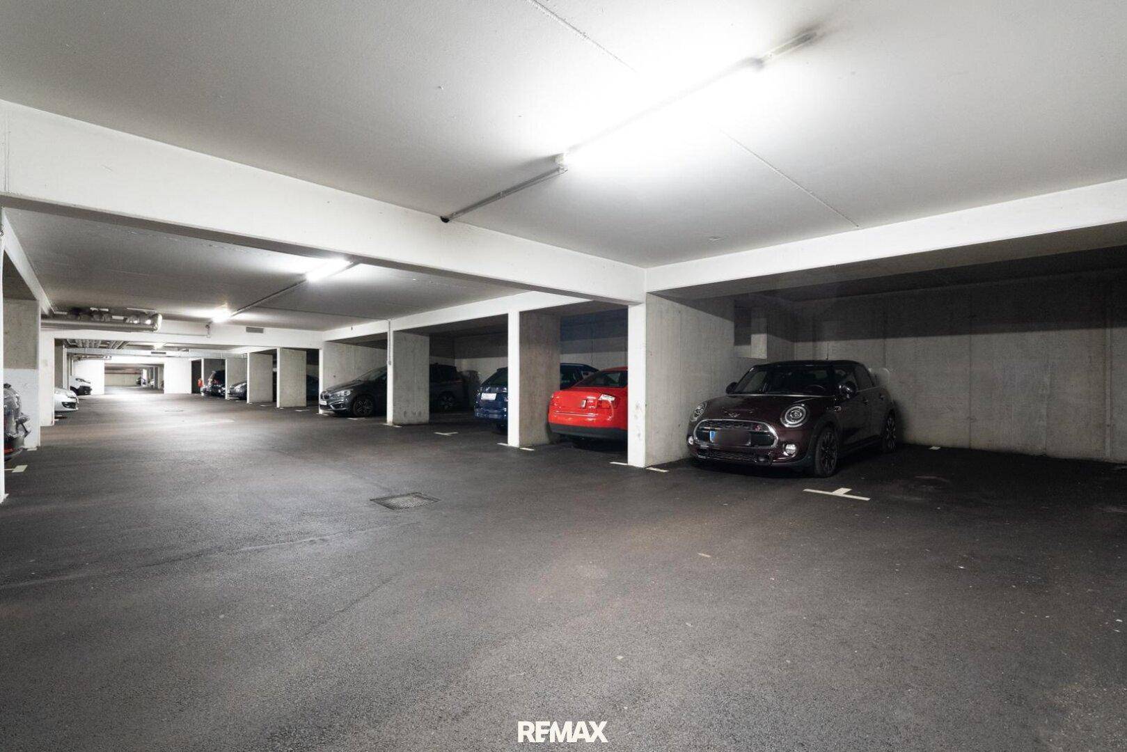 Geräumige Tiefgarage mit mehreren Stellplätzen und heller Beleuchtung.
