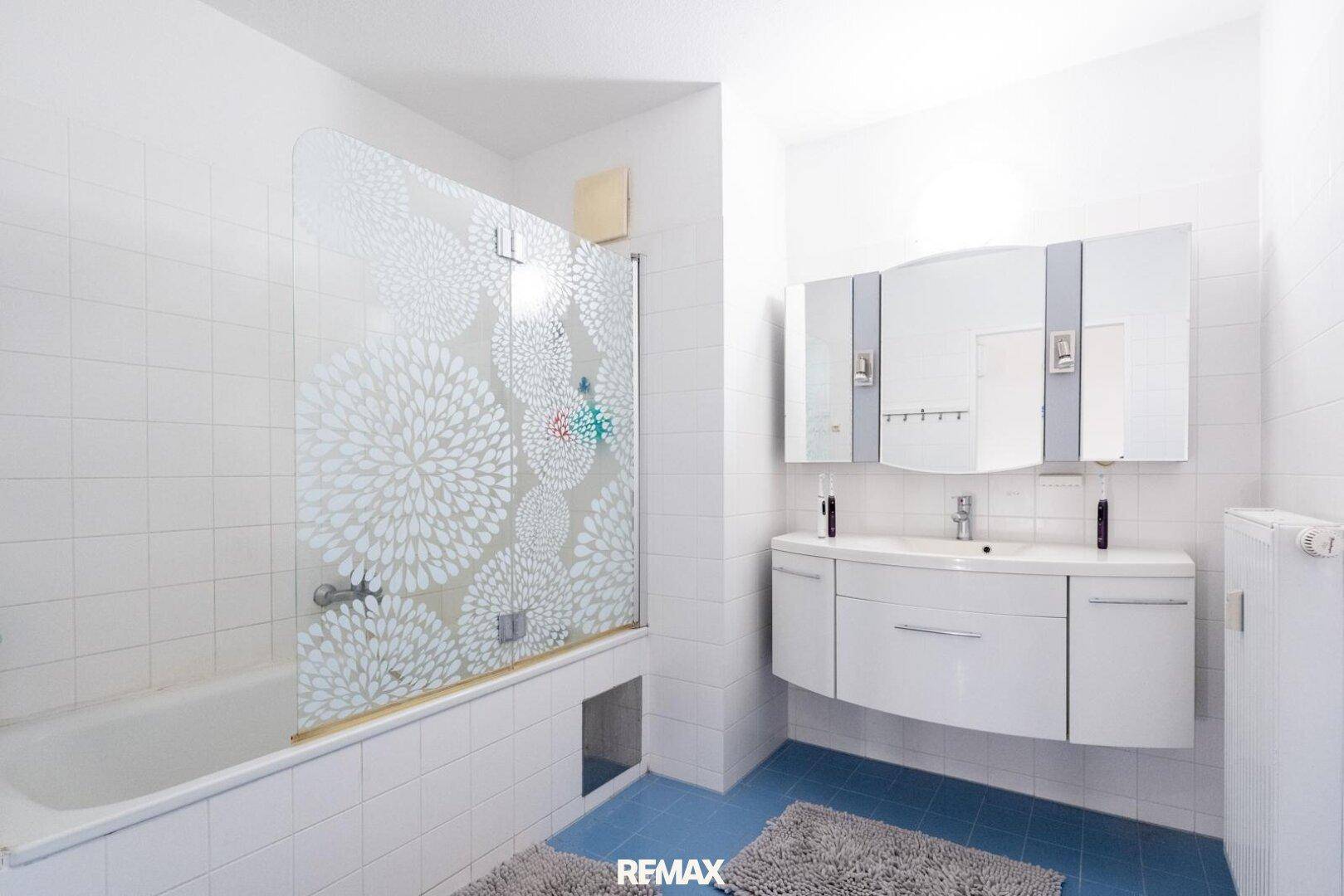 Modernes Badezimmer mit Badewanne, Duschwand und Doppelwaschbecken.