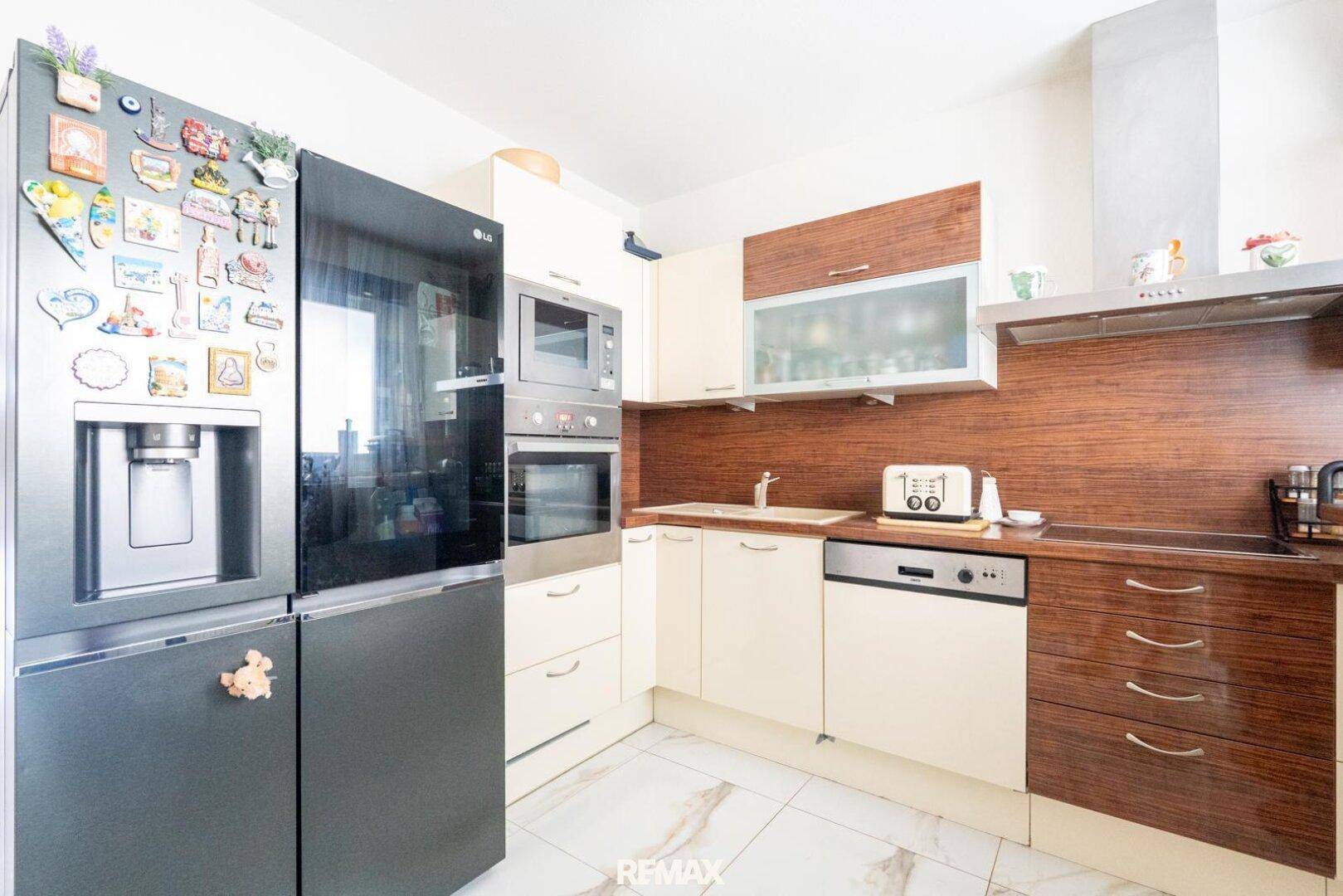 Gut ausgestattete Küche mit großem Kühlschrank, Backofen und Mikrowelle, sowie hellen Schränken.