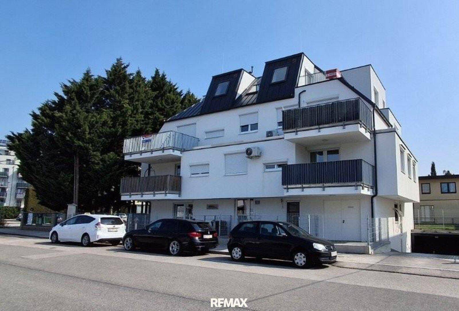 Modernes Mehrfamilienhaus mit mehreren Balkonen und Mansarddach.