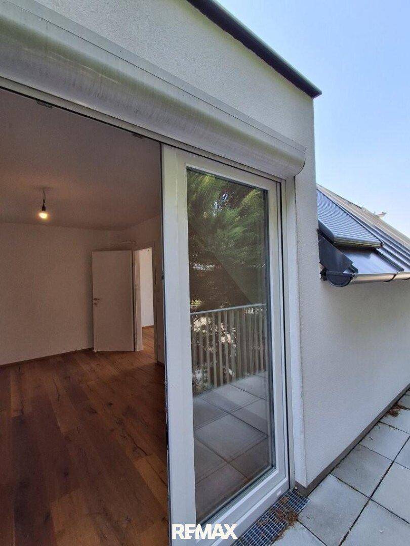 Detailansicht des Balkonzugangs mit Rollladen und Blick auf die Umgebung.