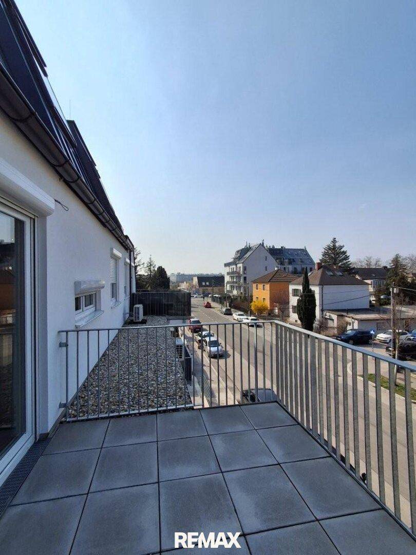 Balkon mit Fliesenboden und Blick auf die Straße und die umliegende Wohnbebauung.