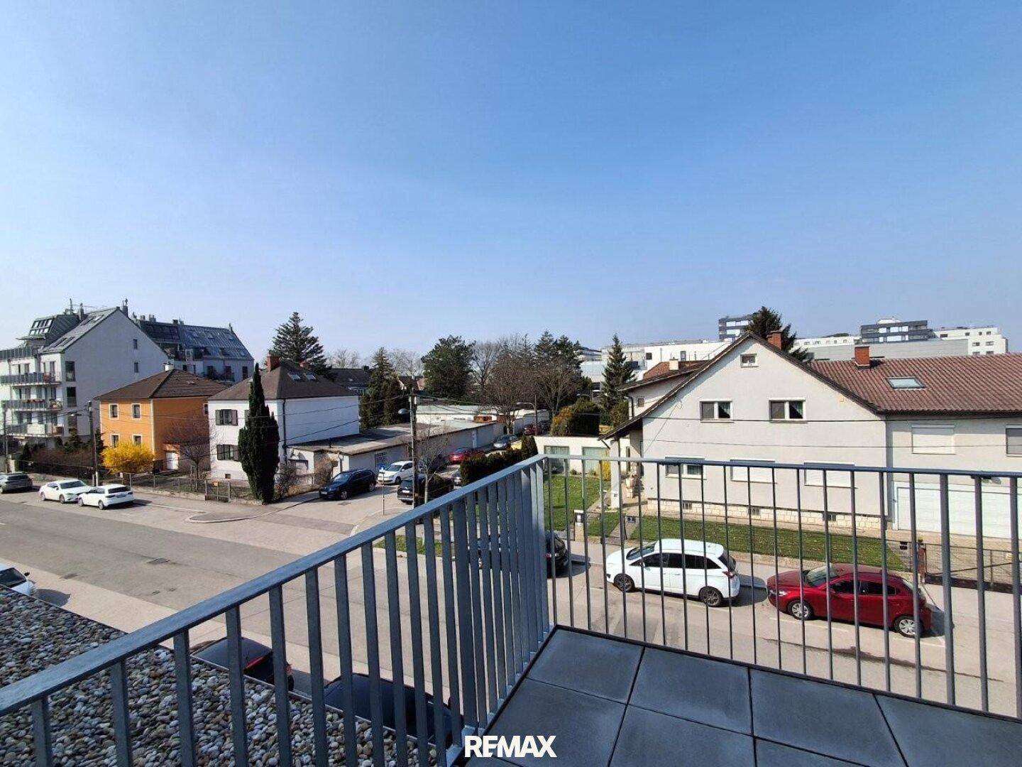 Balkon mit Fliesenboden und Blick auf die umliegende Wohngegend und die Straße.