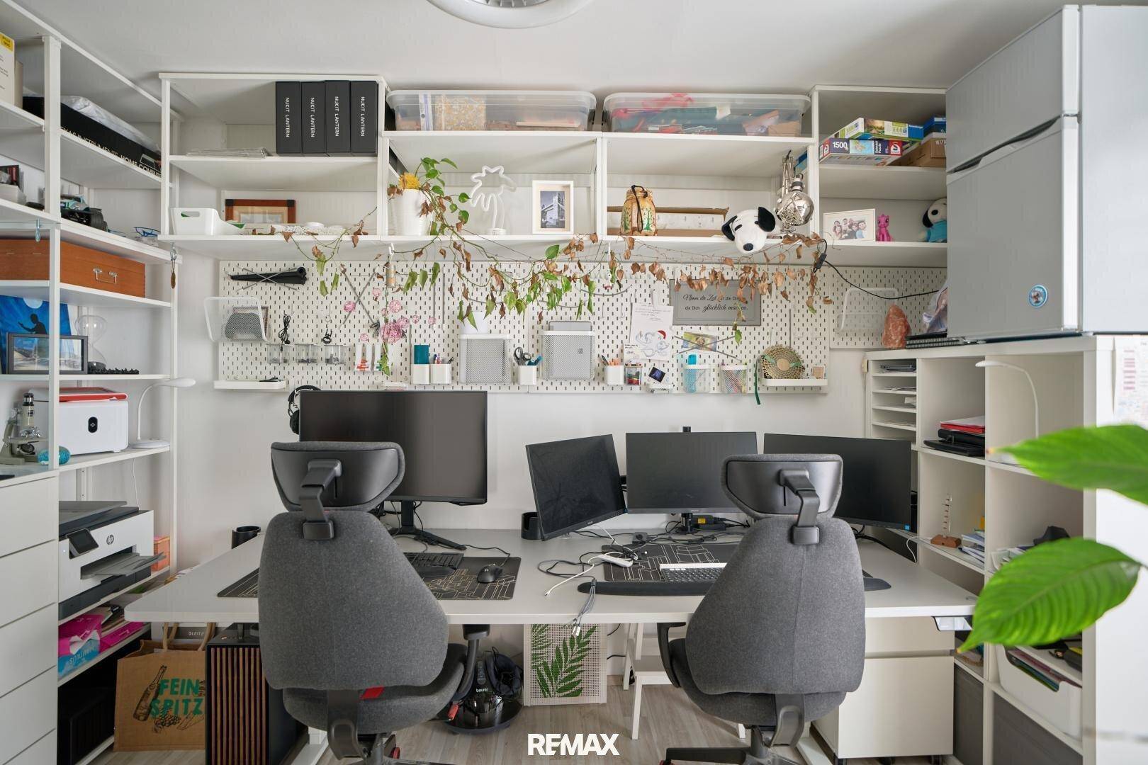 Geräumiges Büro mit mehreren Arbeitsplätzen, Regalen und viel Stauraum.
