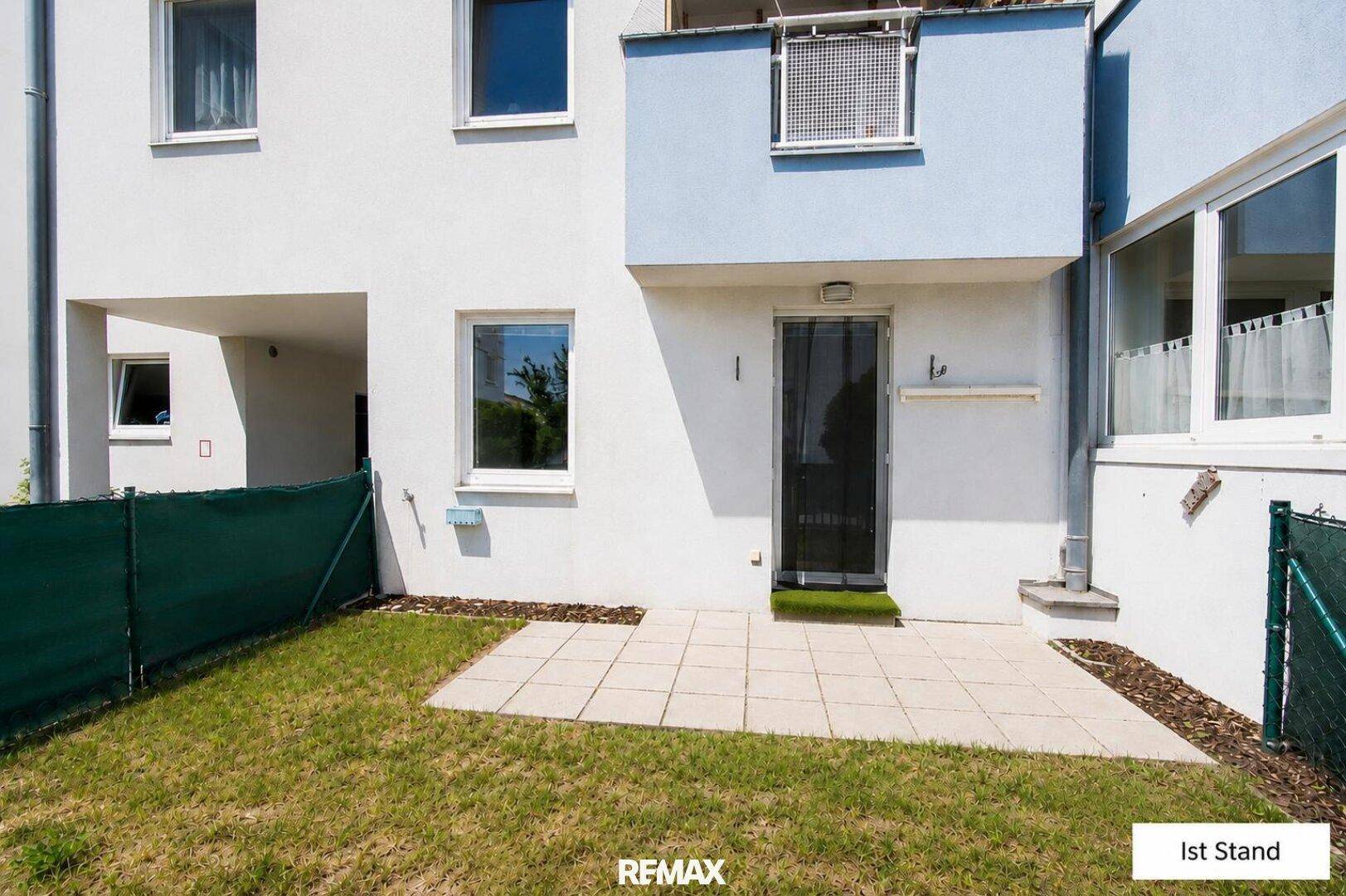 Unmöblierte Terrasse mit Rasenfläche und Zugang zum Gartenbereich des Hauses.