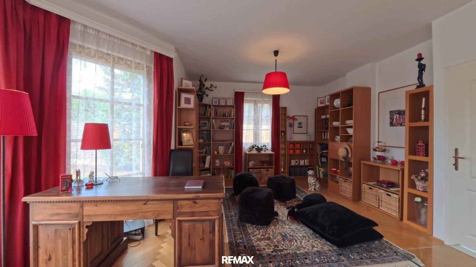 Geräumiges Arbeitszimmer mit vielen Bücherregalen, großem Schreibtisch und Teppich.