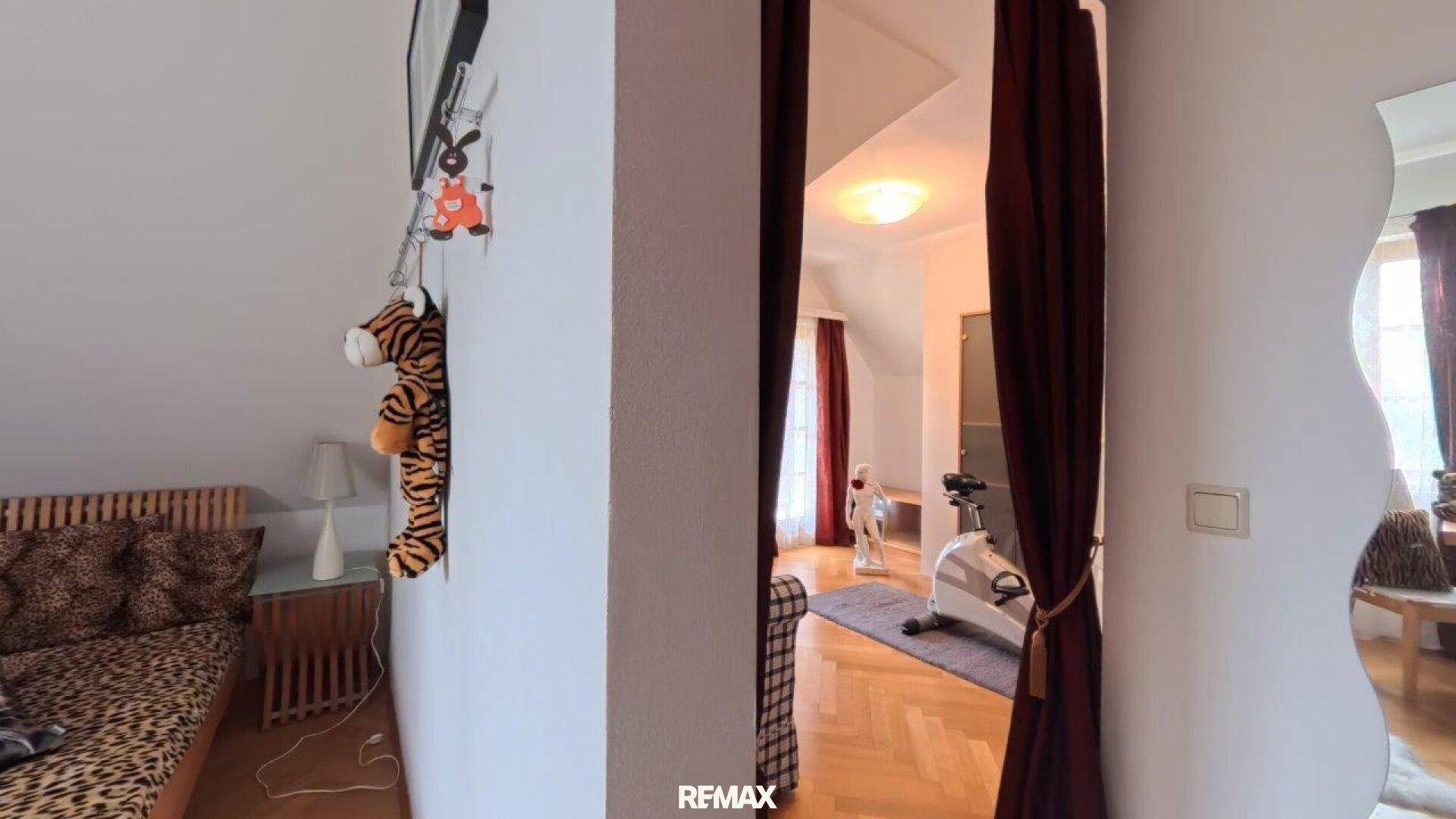 Durchgang zu einem hellen Zimmer im Dachgeschoss mit Fitnessgerät.